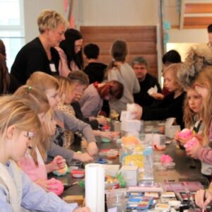 Kinder und Erwachsene basteln gemeinsam an einem langen Tisch – Mitmachaktion der GfG