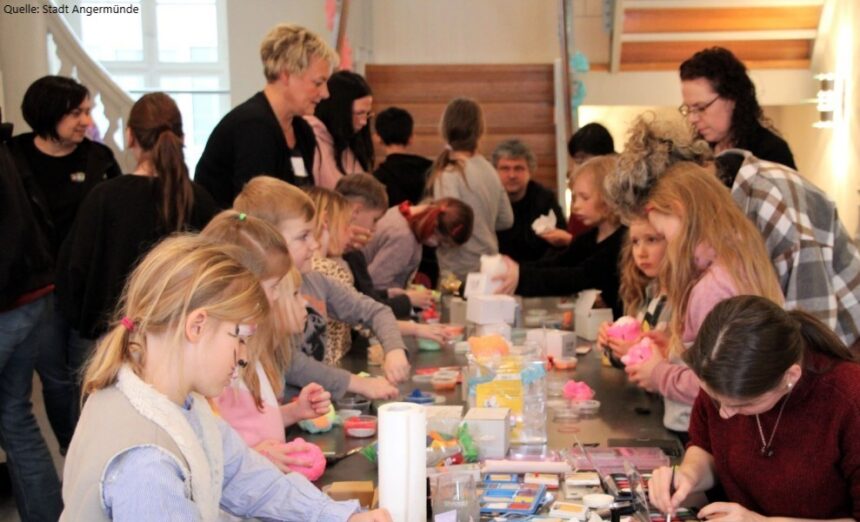 Kinder und Erwachsene basteln gemeinsam an einem langen Tisch – Mitmachaktion der GfG