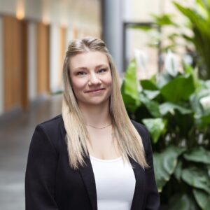 Blonde Mitarbeiterin der GfG mit schwarzem Blazer im hellen Flur